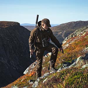 jæger op skrå klippekant med cap, jagt- støvler, bukser og jakke