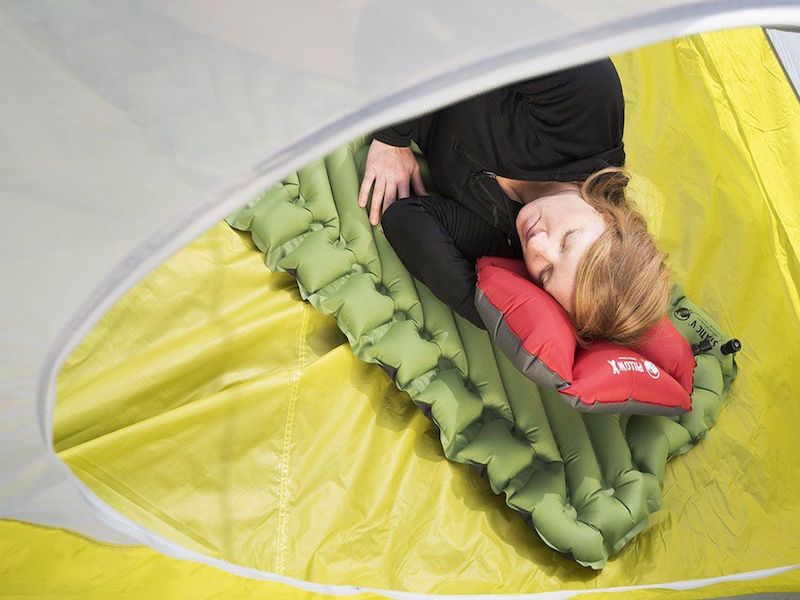 Kvinde ligger i telt på liggeunderlag og hviler
